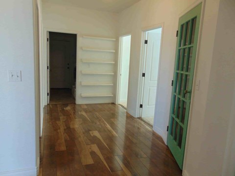 a living room with wood floors and white walls and a green door