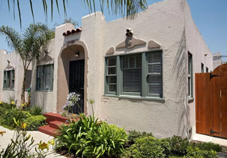a white house with green window shutters and a wooden door