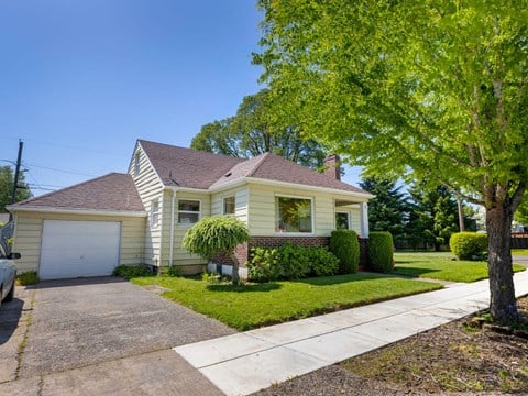 A house with a garage and a tree in front.