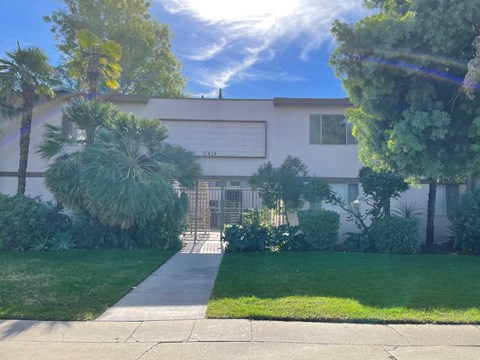 a house with a lawn and palm trees in front of it