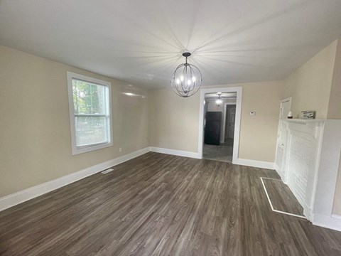 a newly renovated living room with a hard wood floor and a chandelier