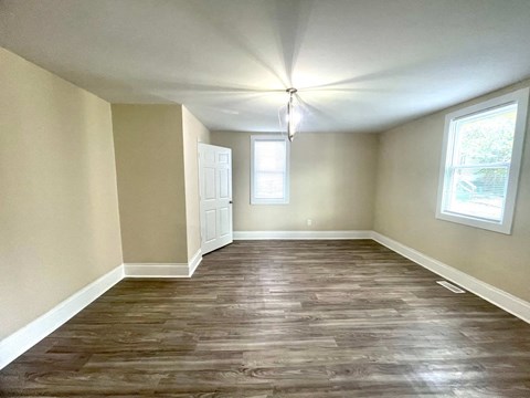 an empty living room with wood flooring and a window