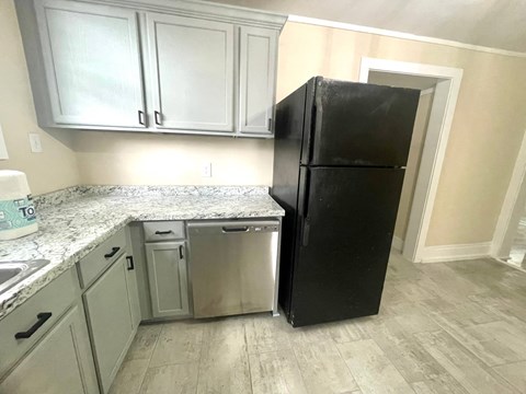 a kitchen with white cabinets and a black refrigerator