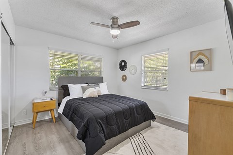 A bedroom with a bed, nightstand, and a ceiling fan.