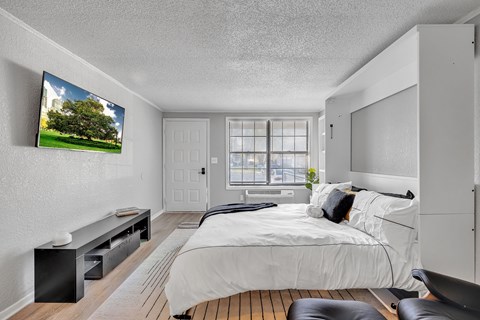 A bedroom with a large bed and a flat screen TV mounted on the wall.