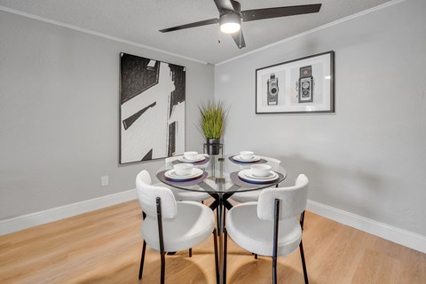 A dining room with a table set for two and two chairs.