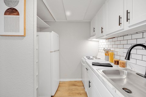 A kitchen with white cabinets and a white fridge.