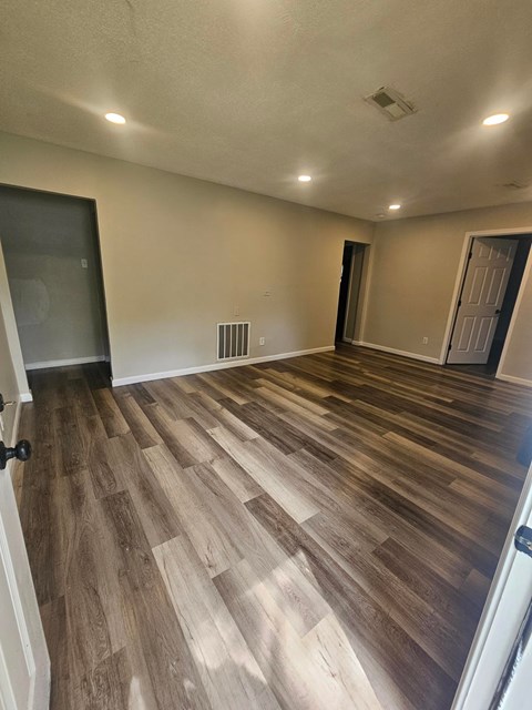 A room with wooden flooring and white walls.