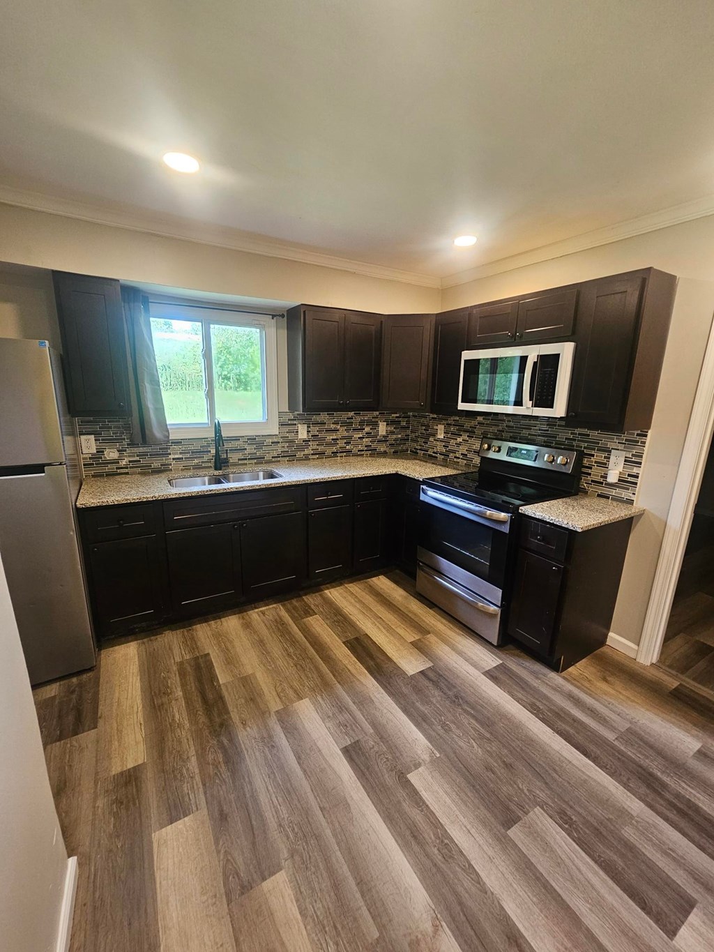 A kitchen with black cabinets and a wooden floor.