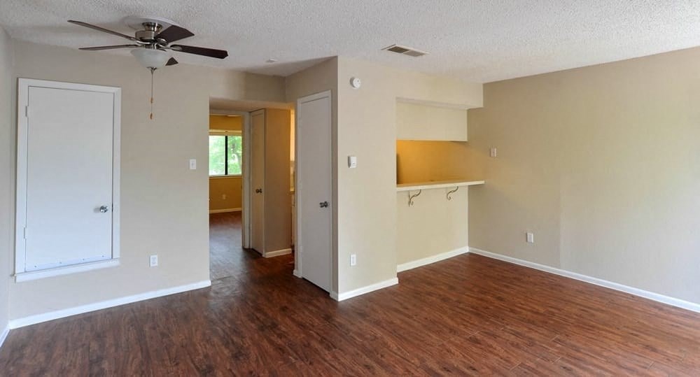 an empty living room with a wood floor and a ceiling fan