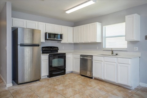 an empty kitchen with stainless steel appliances and white cabinets
