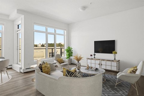 A living room with a large window, a sofa, a coffee table, and a television.