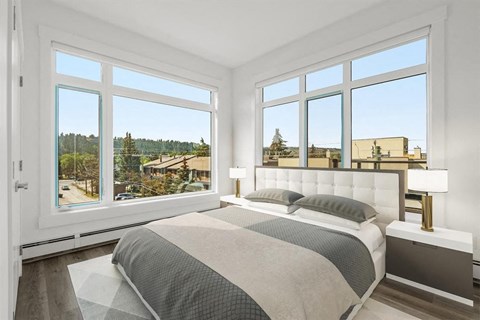 A bedroom with a large bed and a view of the outside through the windows.