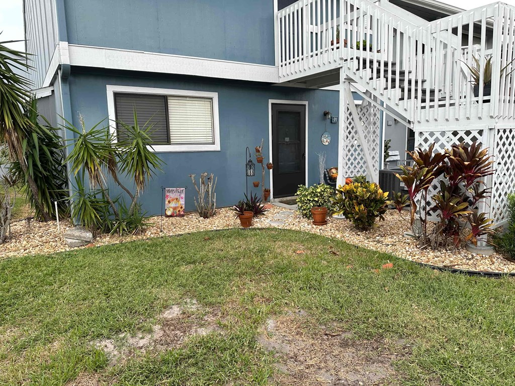the front yard of a blue house with a white balcony