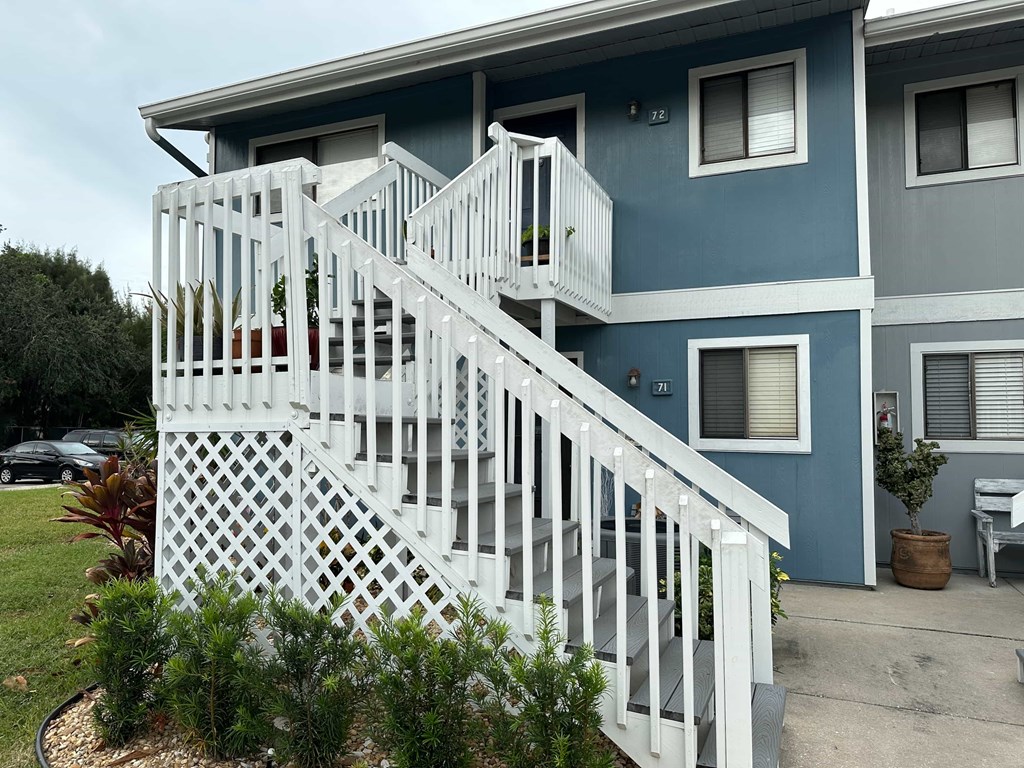 a white staircase in front of a blue house with a white fence