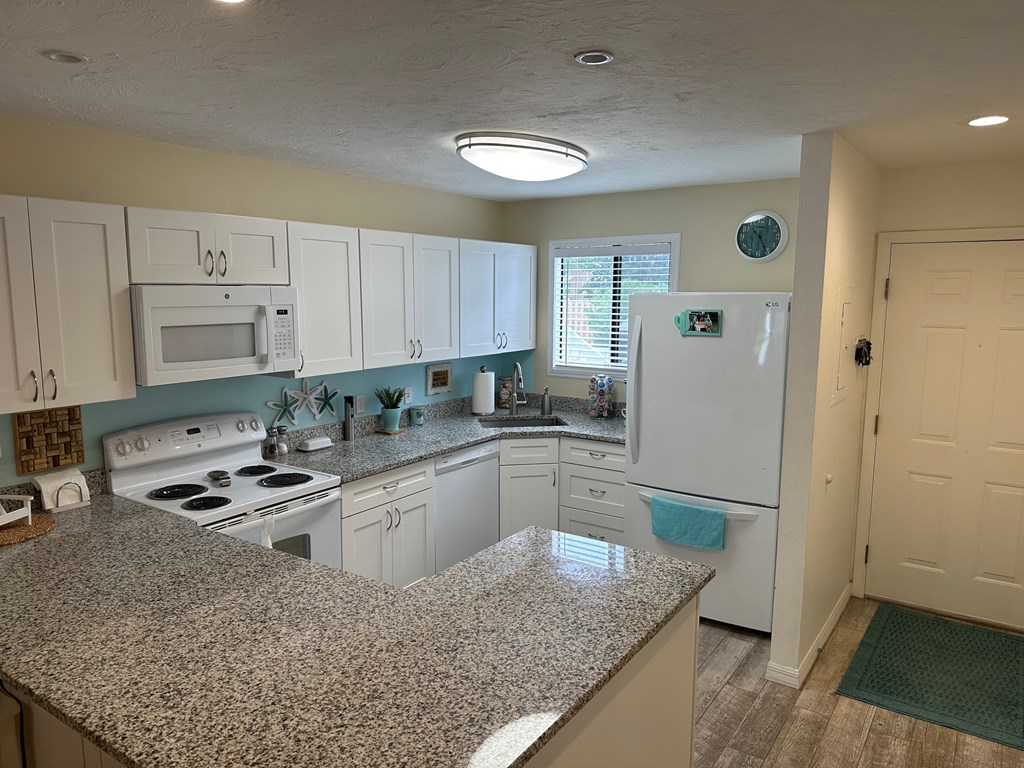 a kitchen with white appliances and granite counter tops