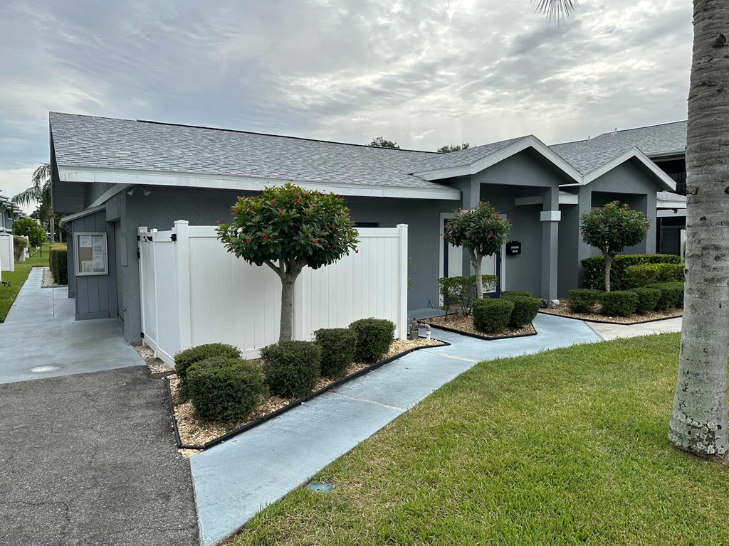 a gray house with a white fence and a driveway