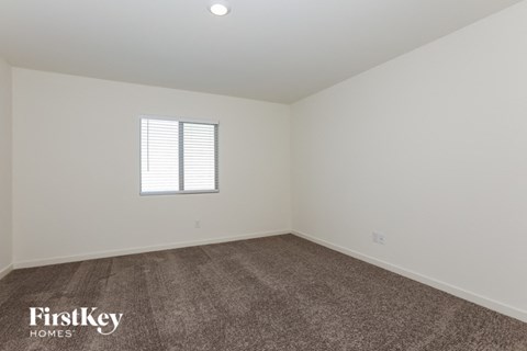 a bedroom with white walls and carpet and a window