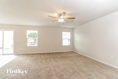 a spacious living room with carpet and a ceiling fan