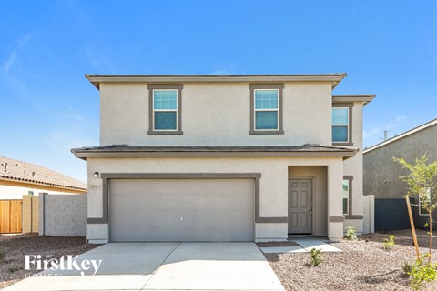 a beige house with a garage door and a sidewalk