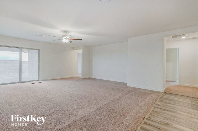 an empty living room with white walls and a ceiling fan