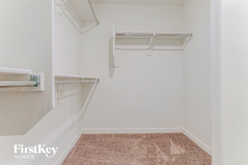 a walk in closet in a white room with two empty shelves
