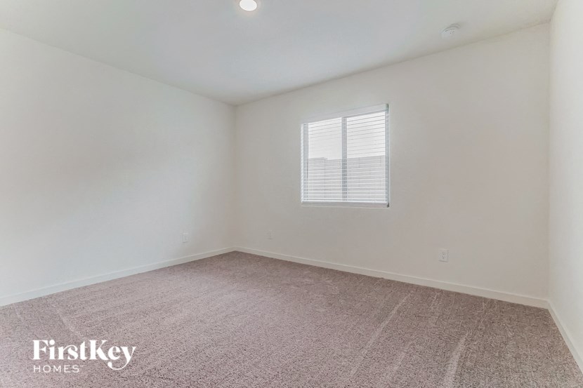 a bedroom with white walls and carpet and a window