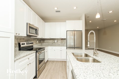 a white kitchen with granite counter tops and stainless steel appliances
