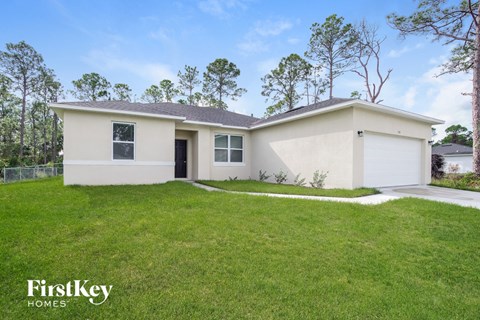 a white house with a grassy yard and a garage