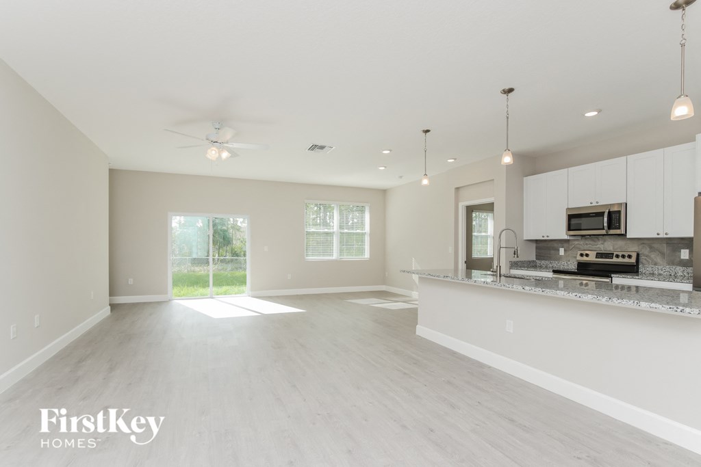 a spacious kitchen and living room with white cabinets and a counter top