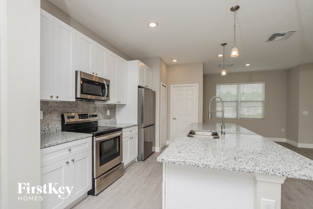 a kitchen with white cabinets and a marble counter top