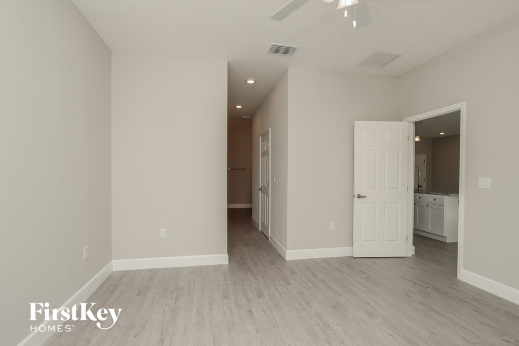a living room with a white door and a hallway to a kitchen