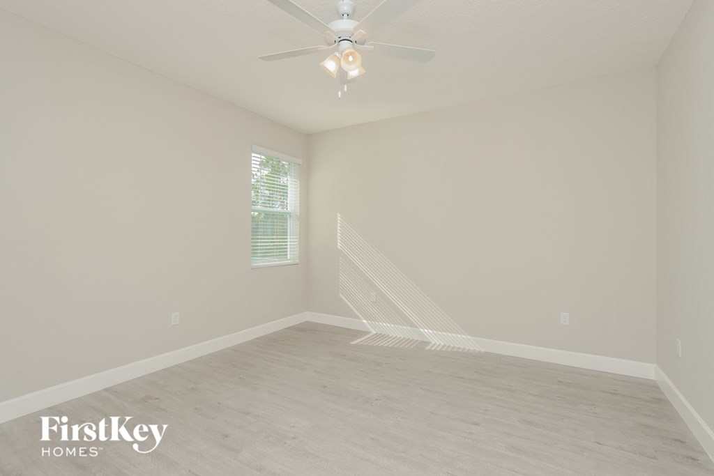 an empty room with a ceiling fan and a window