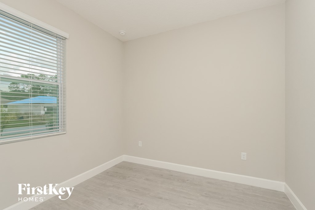 a bedroom with a large window and a wooden floor