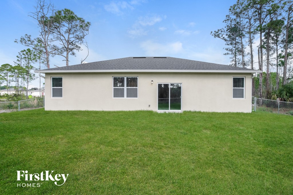 the front of a house with a grass yard and a fence