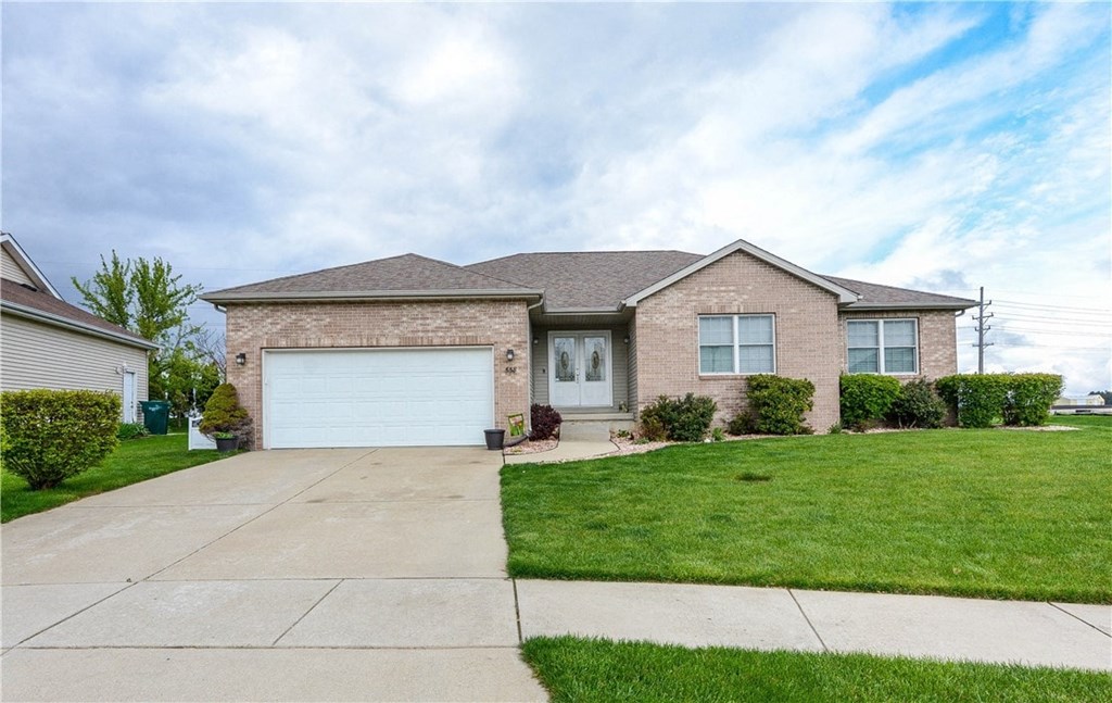 a brick house with a white garage door and a lawn