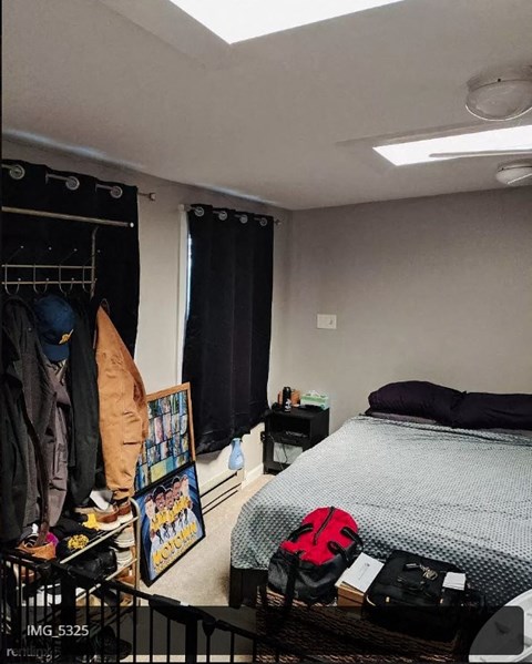 a bedroom with a bed and a rack of clothes in it