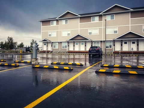A car is parked in a parking lot in front of a building.