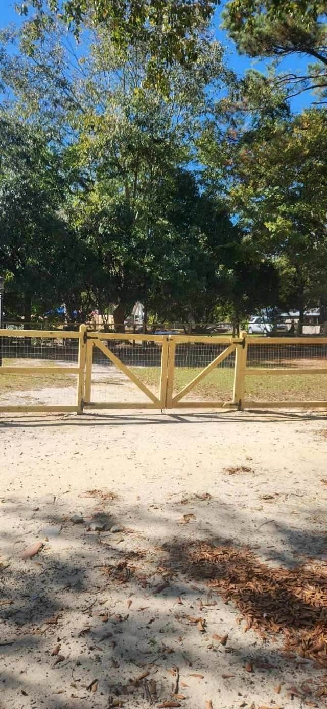 a wooden gate in a park with sand and trees