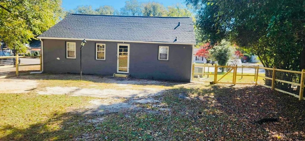 a small house with a fenced in yard and a fence