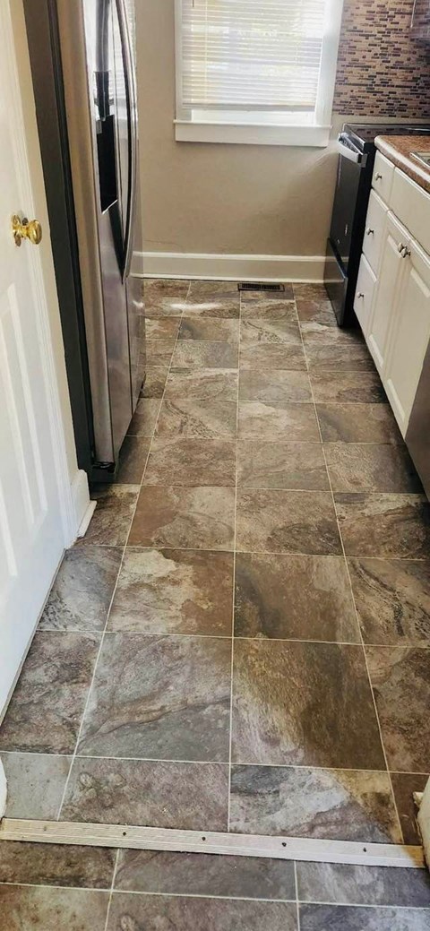a kitchen with tile flooring and a stainless steel refrigerator
