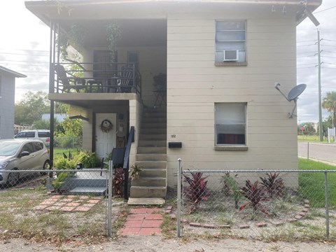 the front of a house with a yard and a fence
