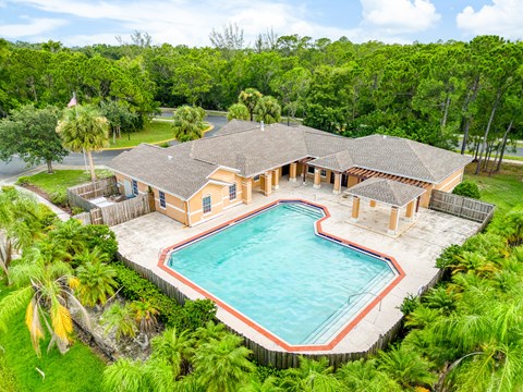 A large house with a pool surrounded by trees.