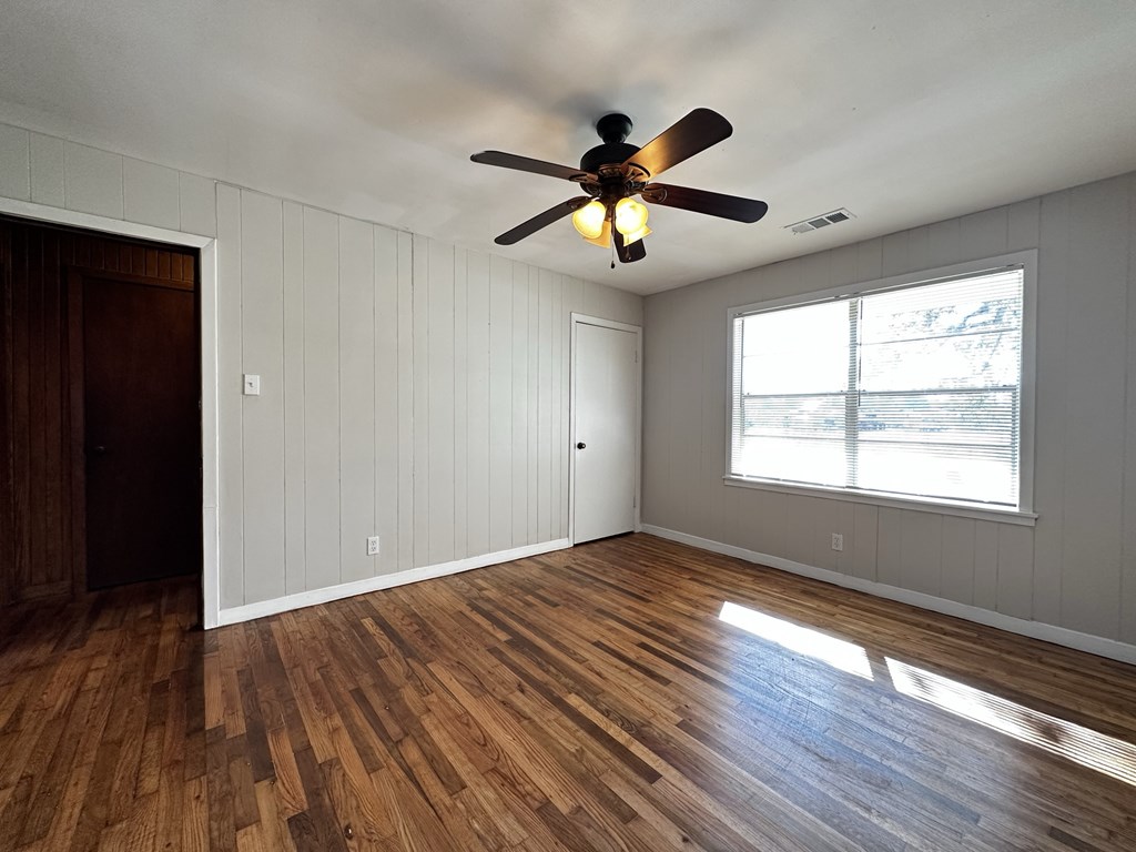 an empty living room with a ceiling fan and a window