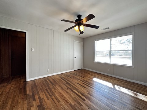 an empty living room with a ceiling fan and a window