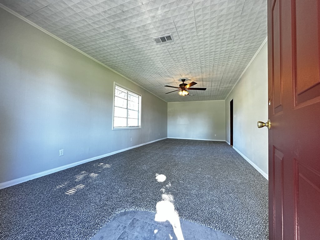 an empty room with a ceiling fan and a door