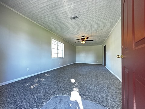 an empty room with a ceiling fan and a door