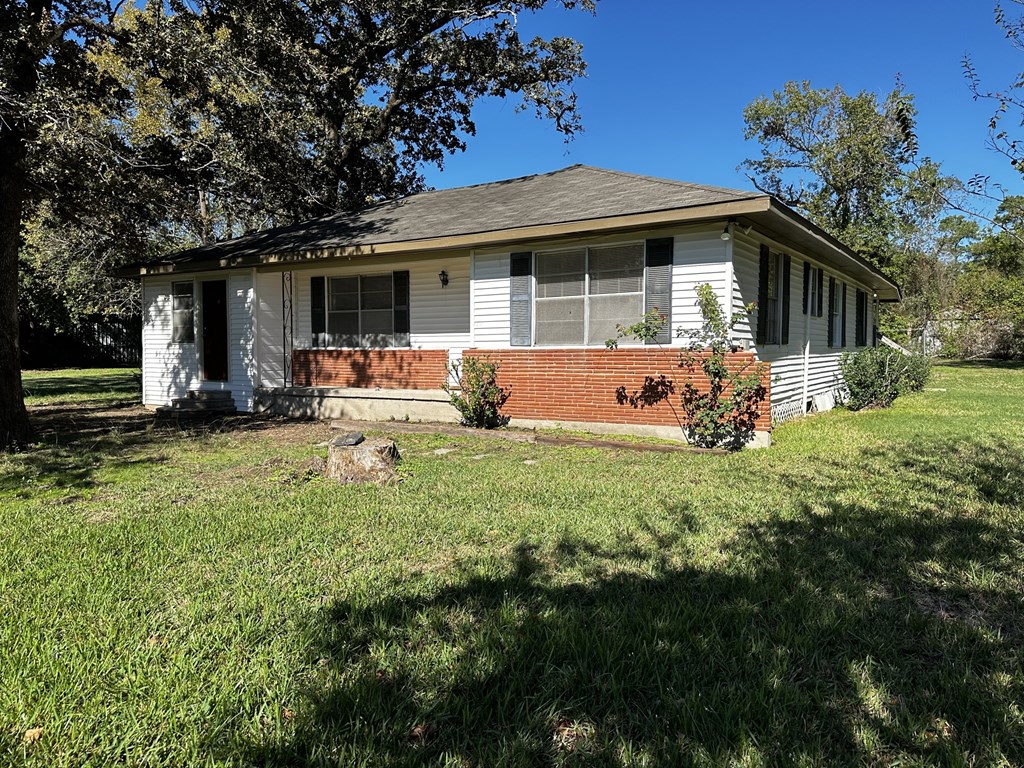 a small white house with a lawn and trees