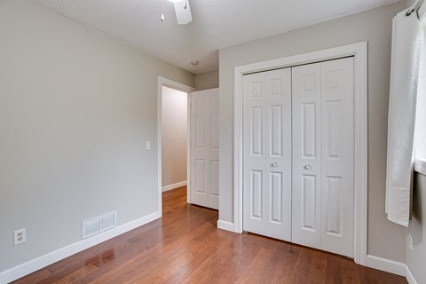 an empty room with white closets and a hard wood floor