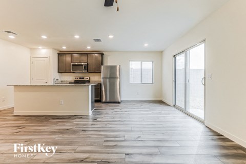 the living room and kitchen of an apartment with wood flooring and stainless steel appliances